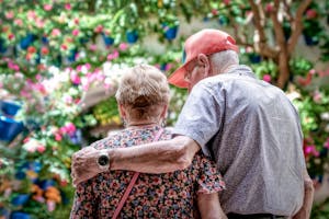 A loving senior couple embraces outdoors in a colorful garden in Córdoba, Spain.